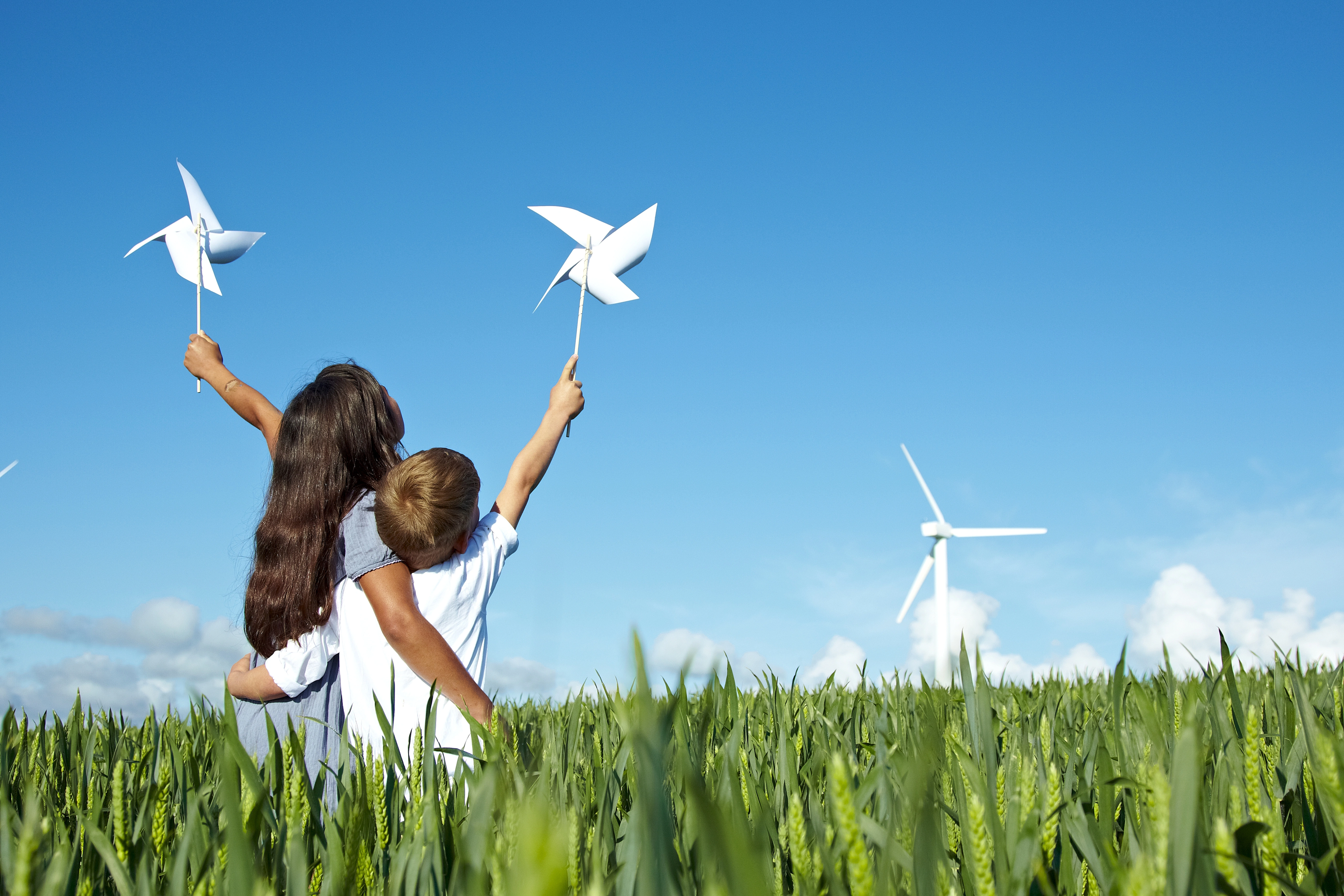 A child and child holding windmills in a field